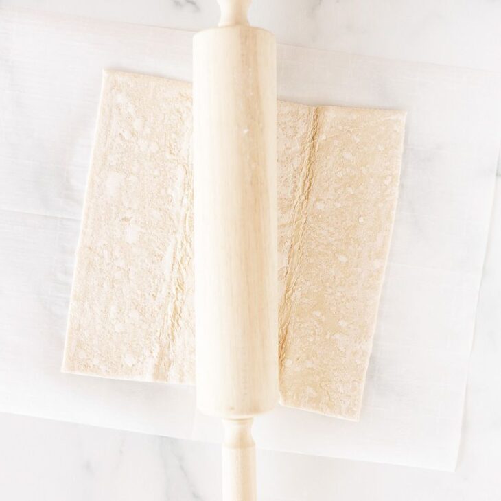 puff pastry on a marble surface with rolling pin