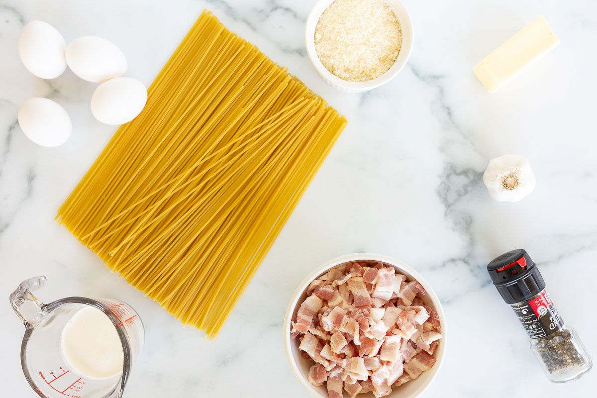 Ingredients for pasta carbonara laid out on a marble surface