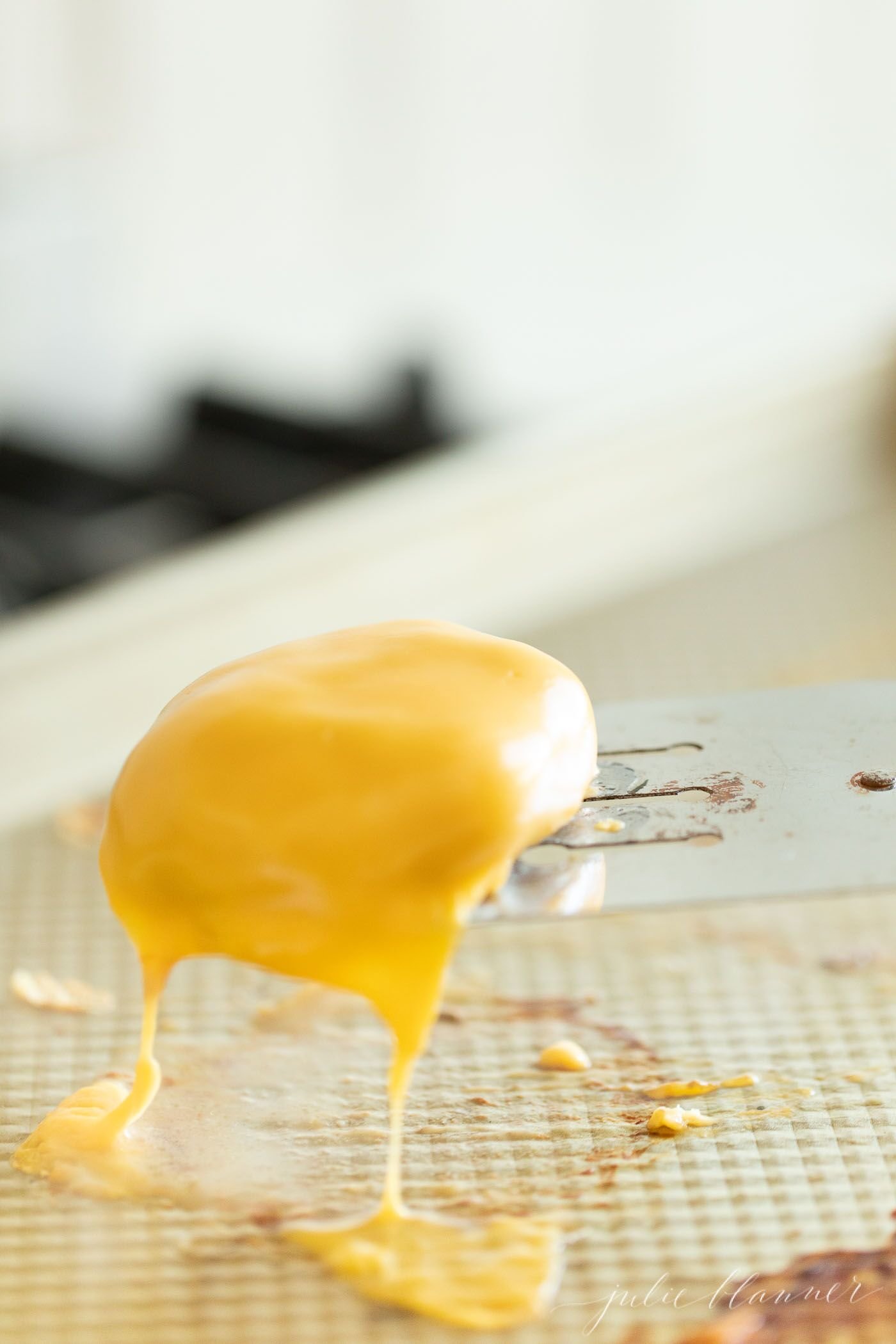 Mini slider burger being lifted off the pan, covered in melting cheese. #sliders #minisliders