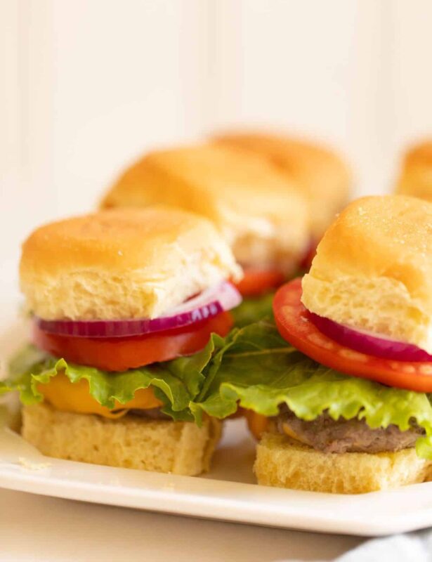 Platter with mini sliders, stacked with onion lettuce and tomato. #sliders