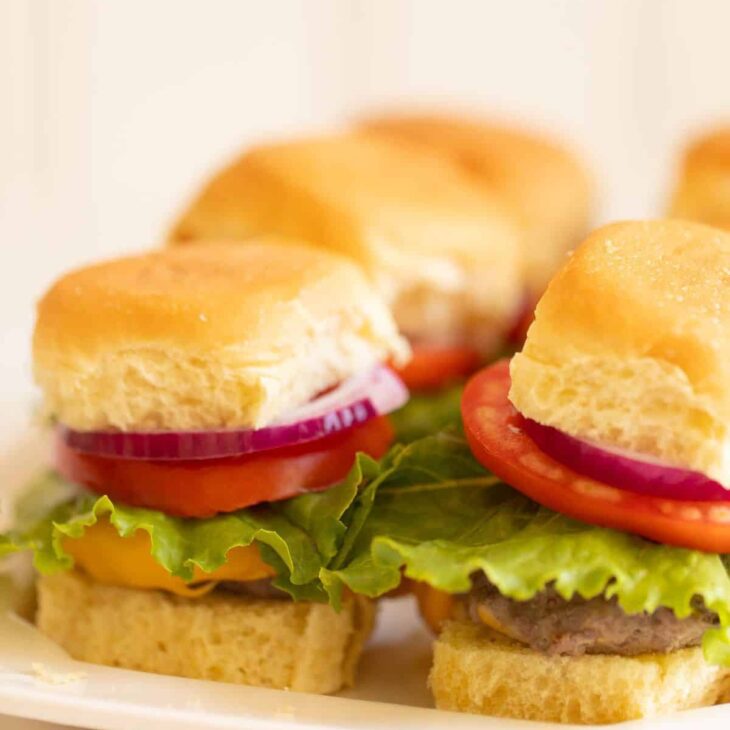 Platter with mini sliders, stacked with onion lettuce and tomato. #sliders