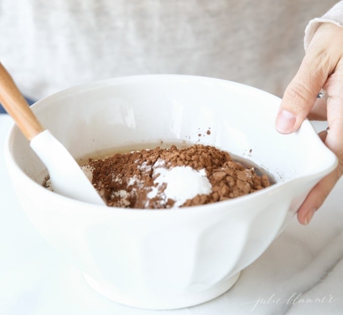 Brownie ingredients being mixed in a white bowl.