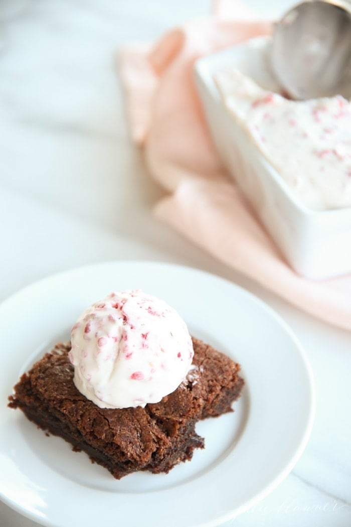 A brownie topped with ice cream on a white plate.
