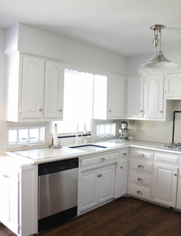 A white kitchen with a wood floor and stainless steel appliances.