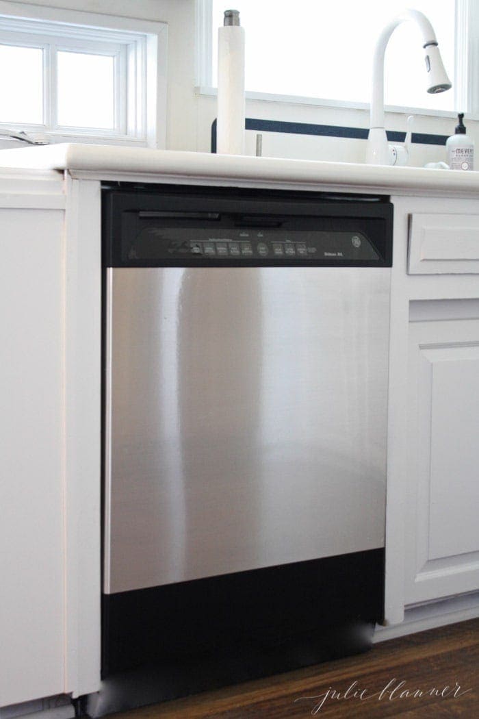 A black dishwasher with a DIY stainless steel panel across the front. 