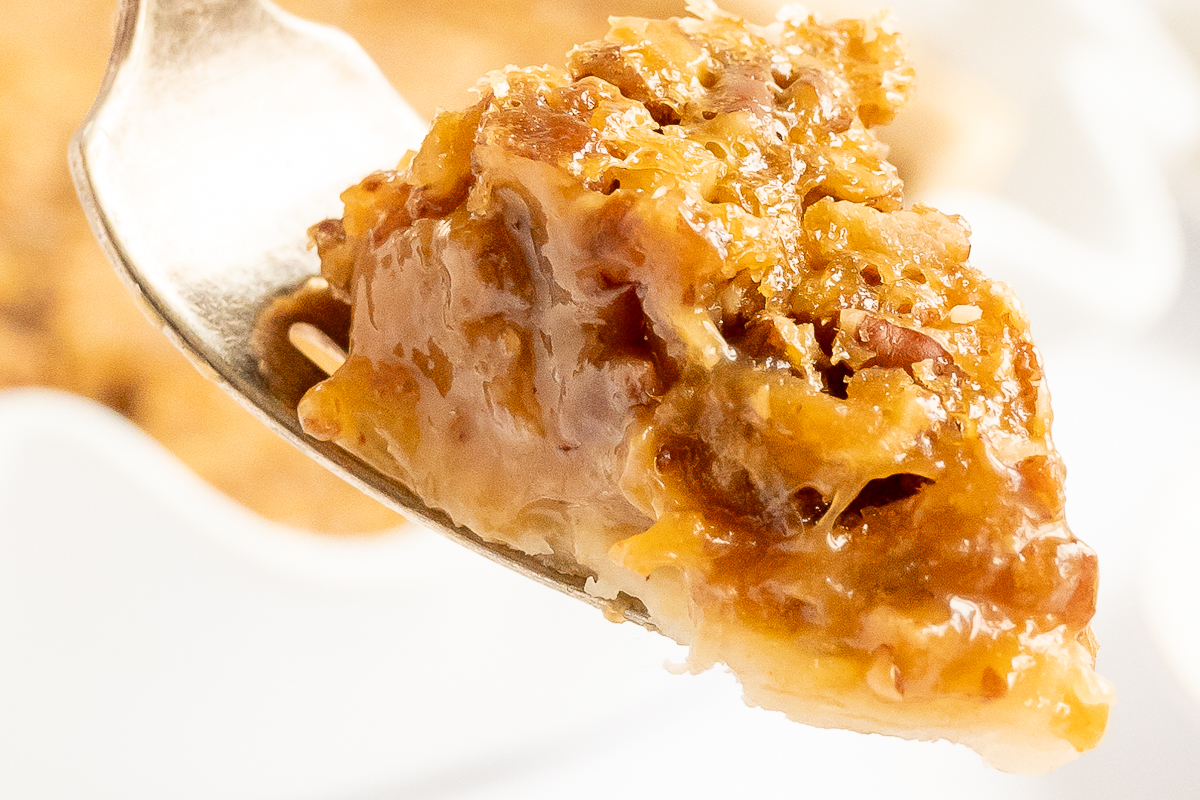 A delicious piece of caramel pecan pie on a fork.