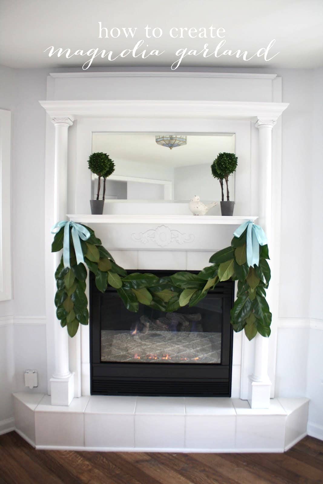 A white fireplace with a handmade magnolia garland hanging from the mantel. 