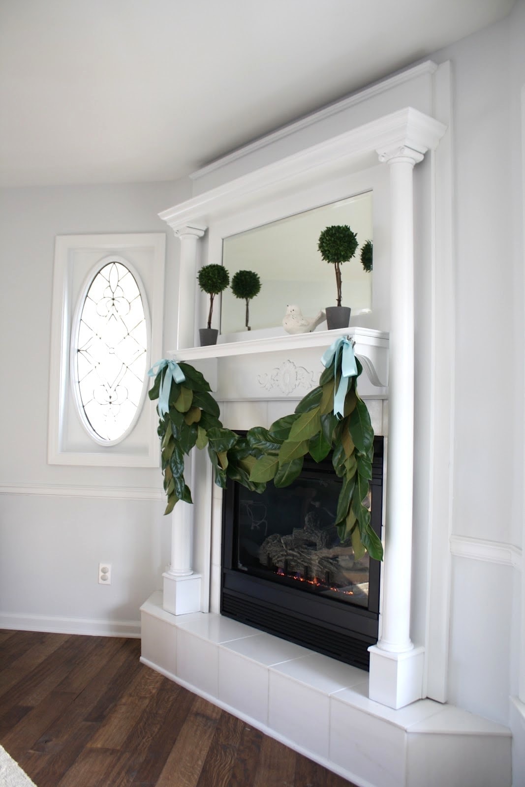 A magnolia garland hanging on a white fireplace mantel.