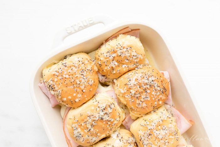 Seasoned Ham and Cheese Sliders in a white dish, before being cooked.