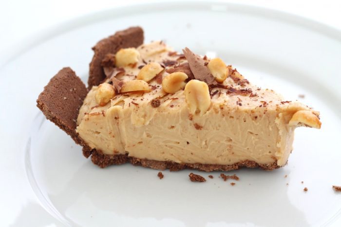 An easy No Bake Peanut Butter Cheesecake recipe tucked inside an Oreo or chocolate graham cracker crust. Creamy, crunchy, and decadently rich. slice of easy no bake peanut butter cheesecake on white plate