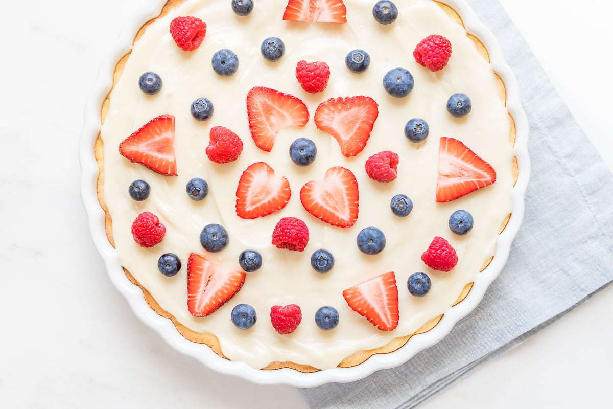 A close up of a fruit pizza with cream cheese fruit pizza icing on top.