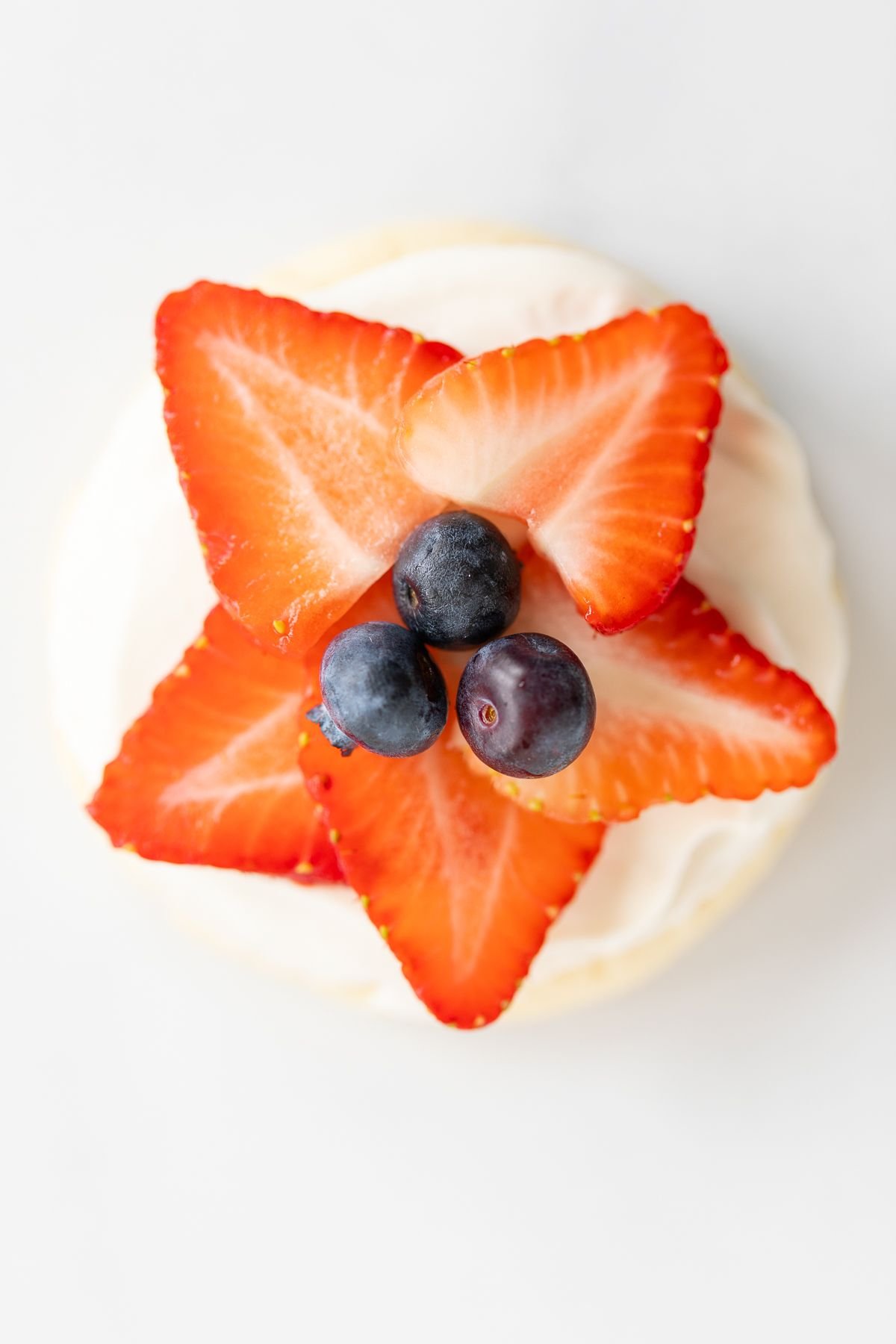 A fruit pizza cookie with strawberries and blueberries on top in the shape of a star