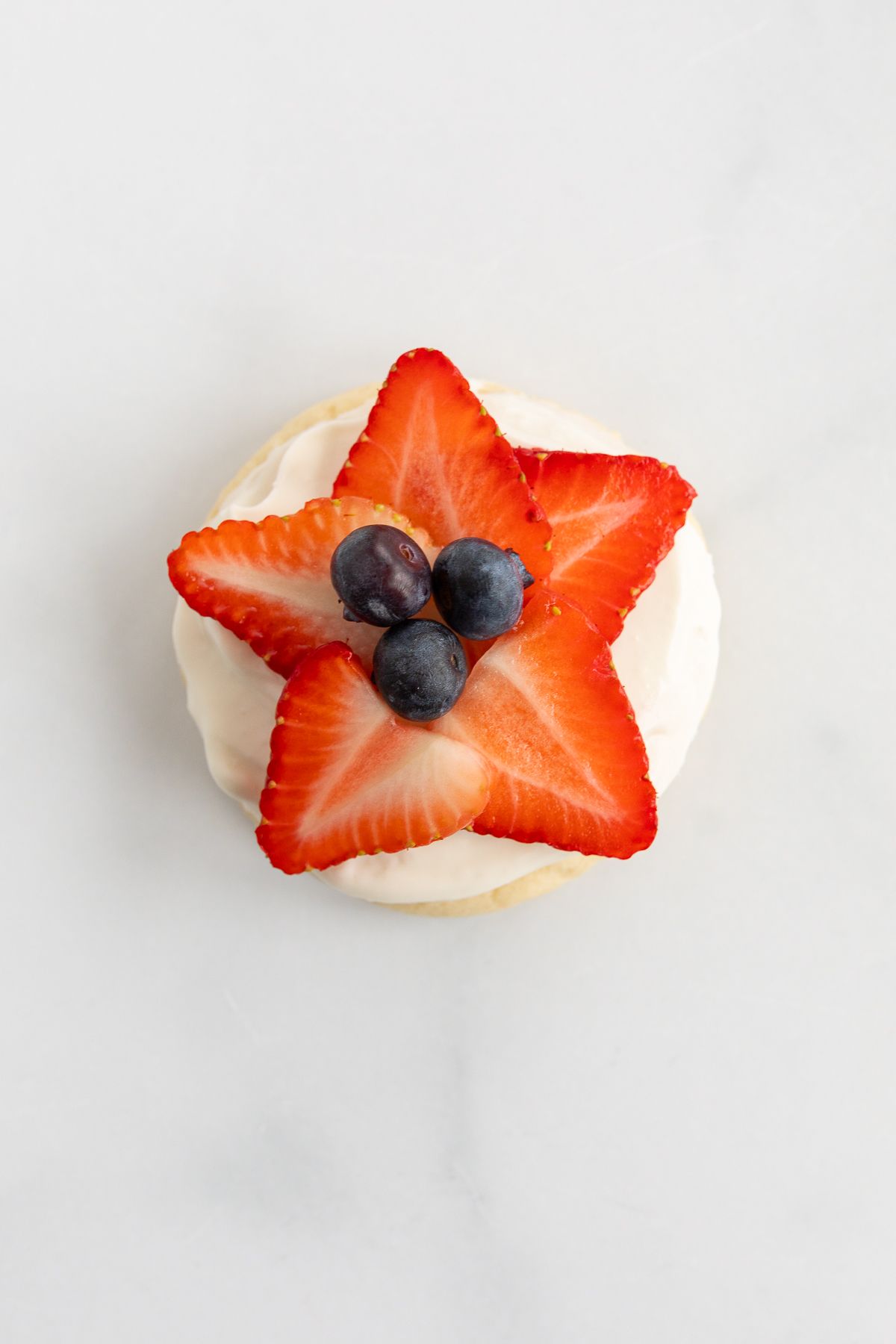 A fruit pizza cookie with strawberries and blueberries on top in the shape of a star