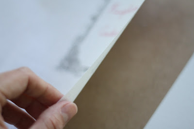 A piece of paper, hand pulling back fabric to separate it.