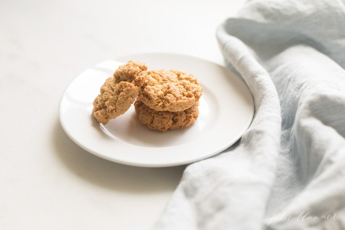 A white plate on a white counter, filled with healthy peanut butter cookies.