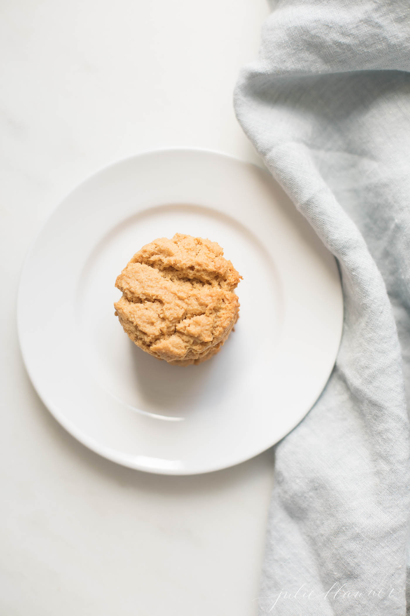 A white plate with a stack of healthy peanut butter cookies, blue napkin to the side.
