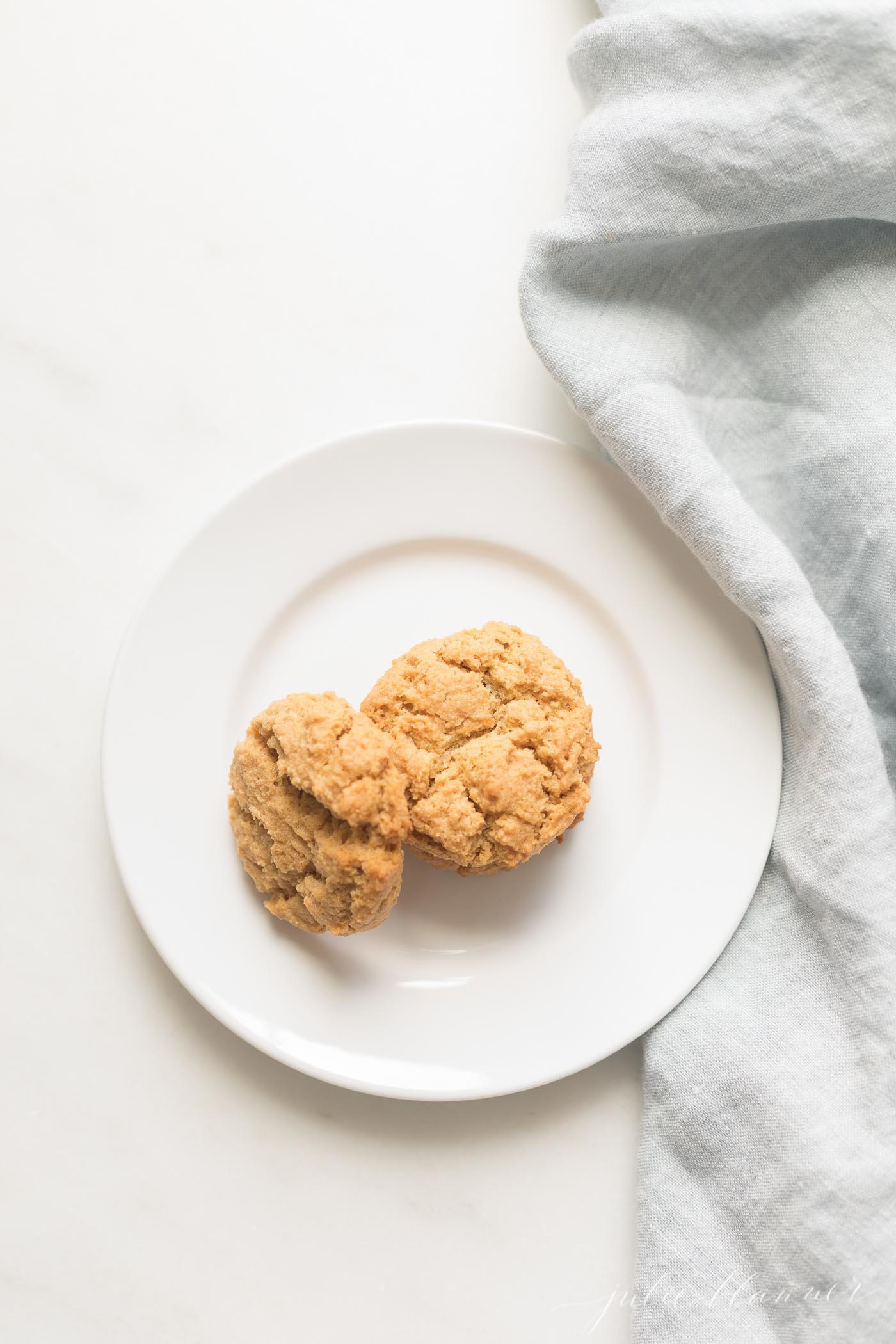A white plate with low calorie peanut butter cookies, linen kitchen towel to the side.