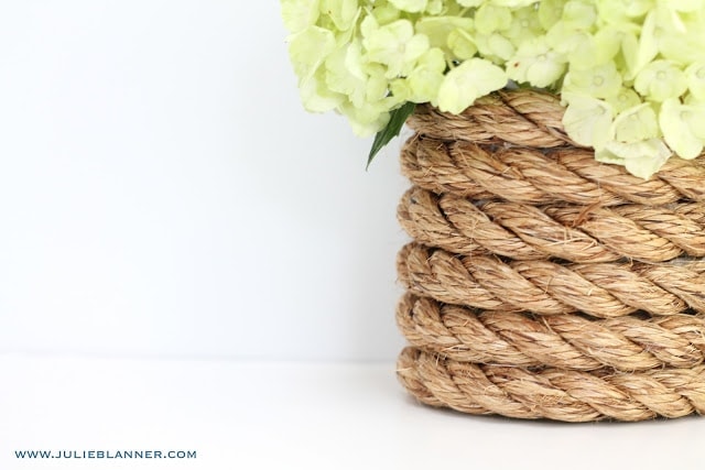 On half of the picture, the nautical rope vase filled with light green hydrangeas is seen, while the other side is just a white background.