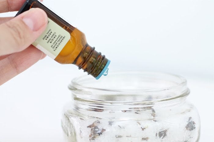 Essential oil being poured into a glass jar.