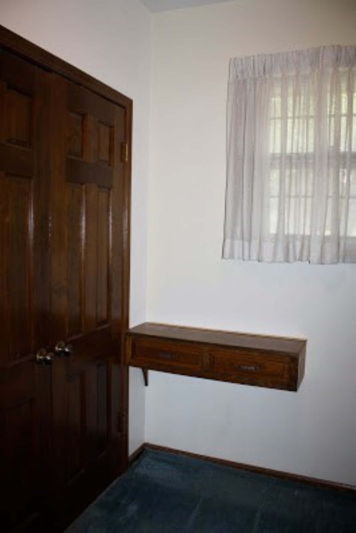 A before shot of a mudroom laundry room makeover with dark wood trim on the doors.