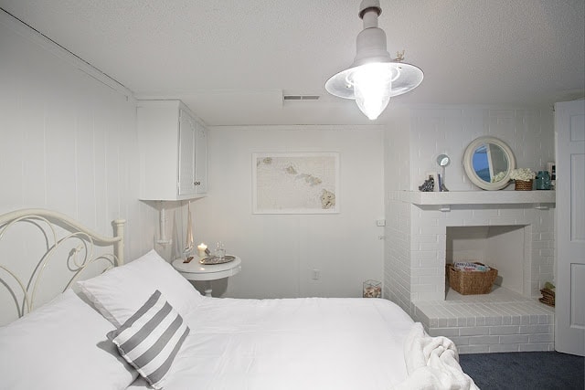 A white bedroom with various things on walls and shelves