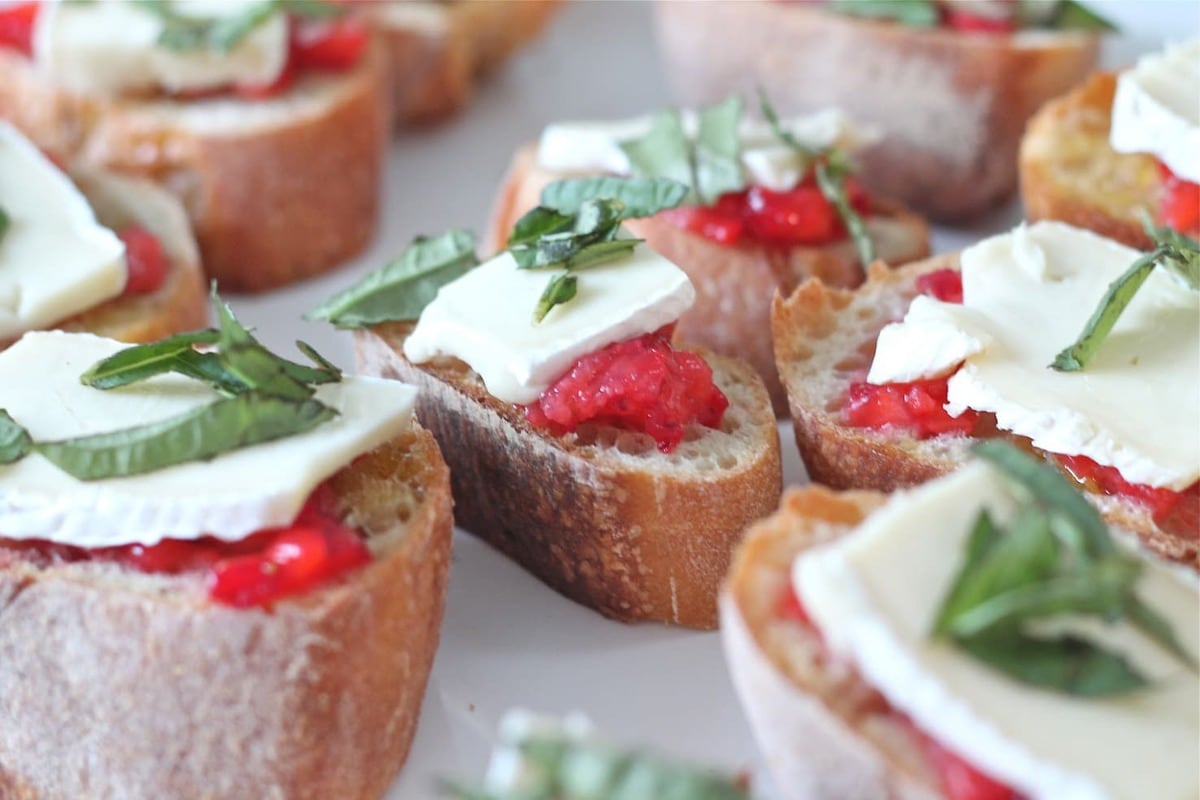 A plate of bruschetta topped with strawberries and brie