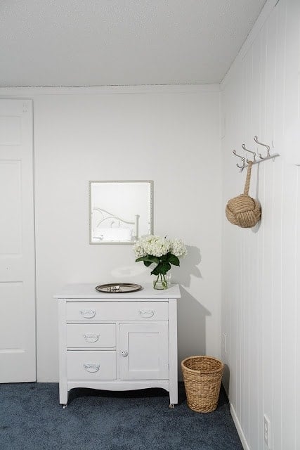 A bedroom with a small dresser and a mirror