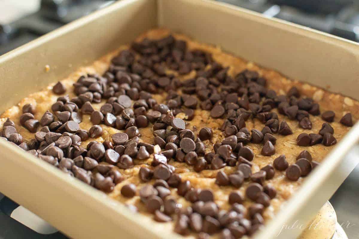 chocolate chips on top of oatmeal cookie dough in baking dish