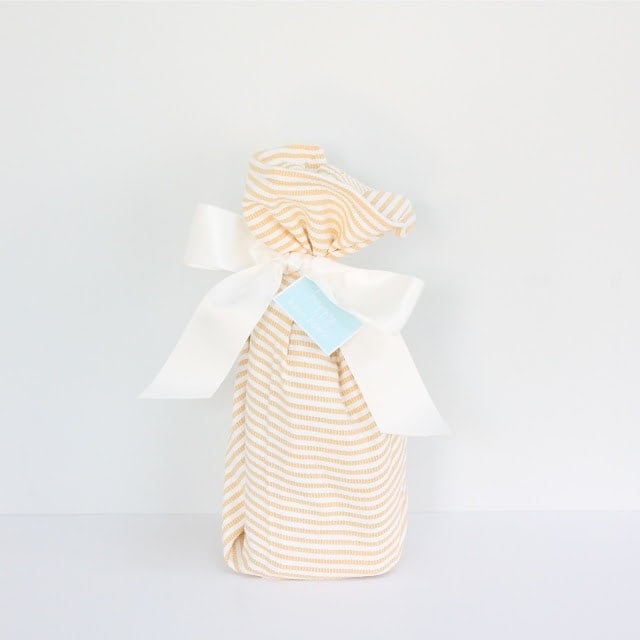 A wrapped gift with a white ribbon and a \'happy new home\' tag.