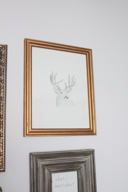 A brass picture frame with a deer in it on the wall.