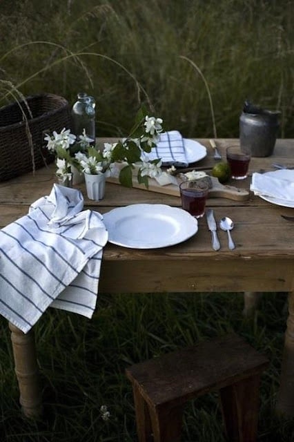 wood table outside in grassy area set with flowers