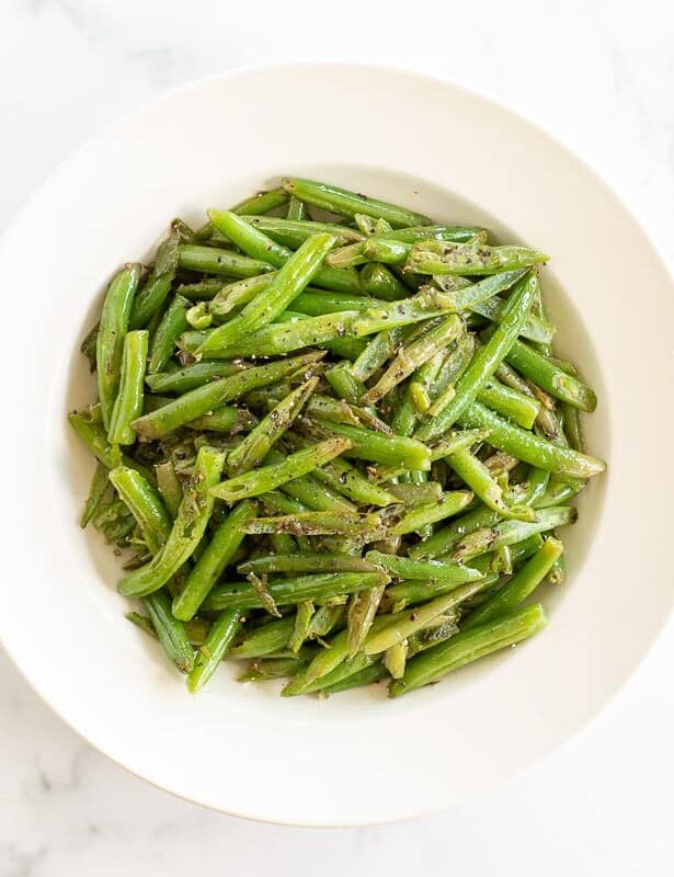 A white bowl full of seasoned green beans.