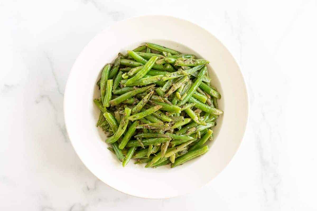 A white bowl full of seasoned green beans.