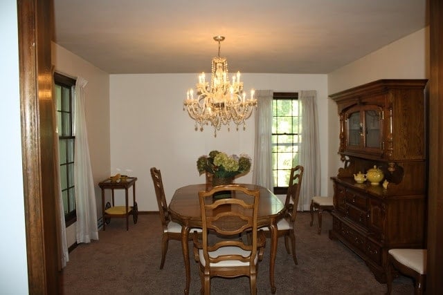 A wood dining room table with a big chandelier hanging over the top.