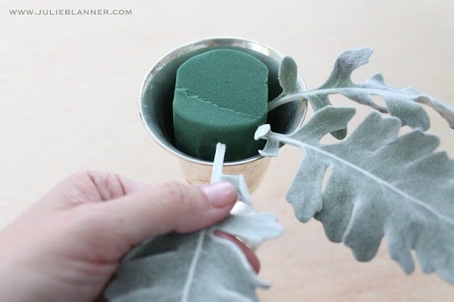 Green leaves being stuck in floral foam