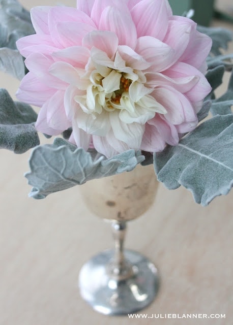 A silver vase with pink and white flowers on a table.