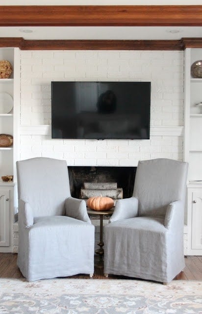 A living room with two gray chairs with a TV over them