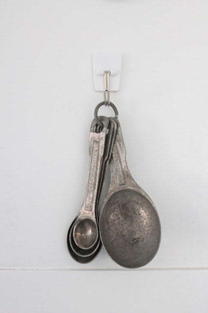 Measuring spoons hanging from a hook inside a spice cabinet