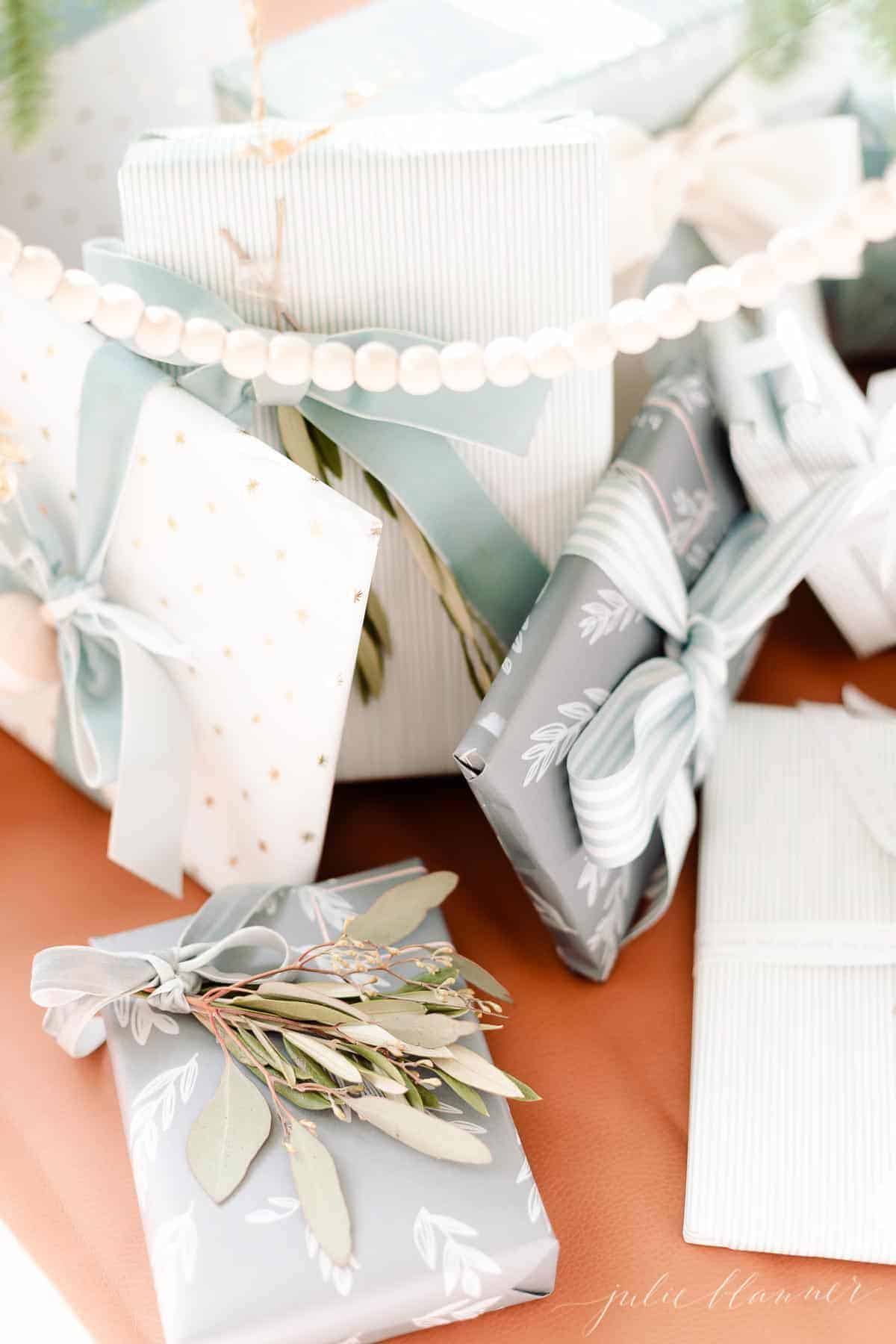 Blue and white gifts under a tree with a wooden garland hanging in front.