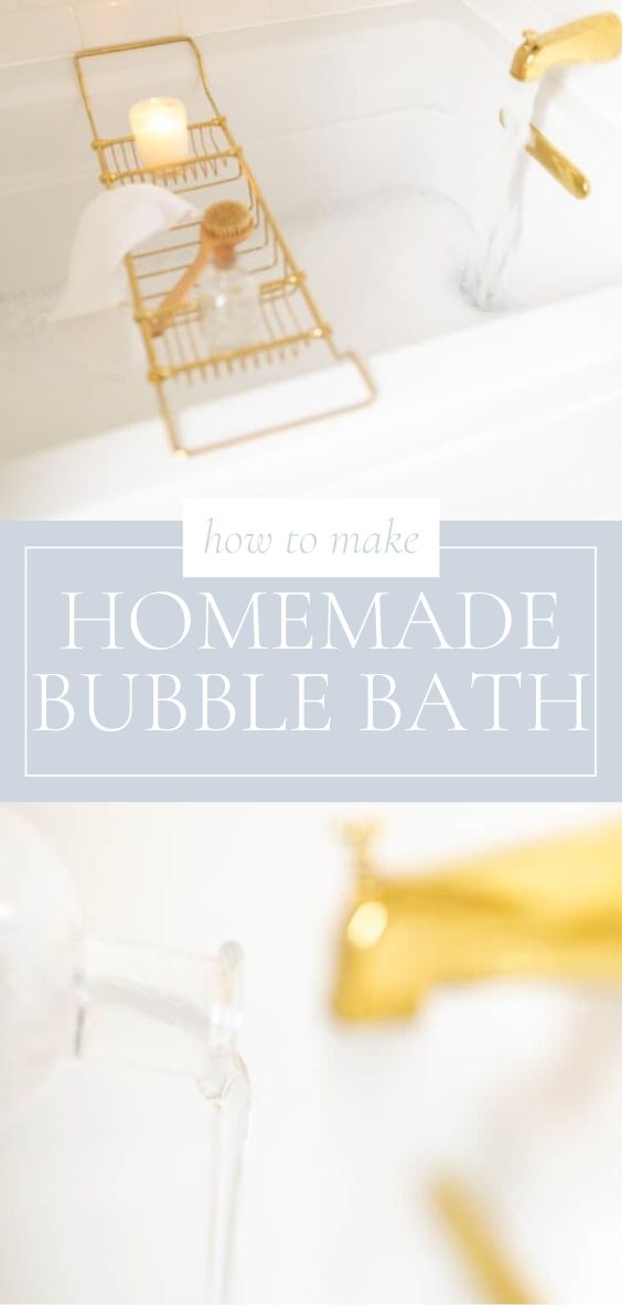 In a bath tub, there is a golden faucet flowing water, a golden bath rack across the width of the white tub holding a candle, wooden scrubber, a white bath cloth, and glass bottle of bubble bath with a corked top.