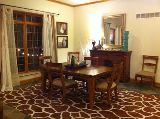 A wood dining room table with a brown carpet underneath