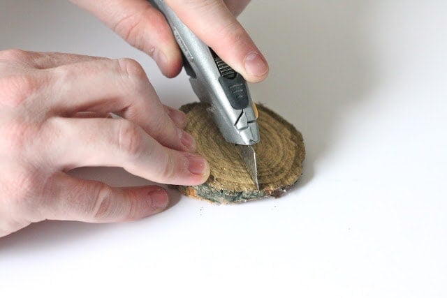 hands using a razor blade to cut through wood chip