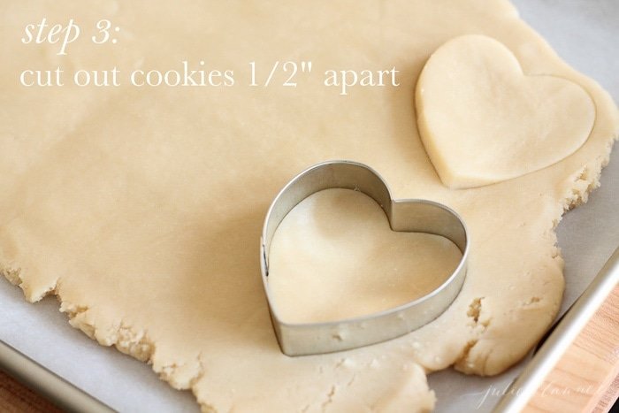 Sugar cookies being cut into the shape of a heart.