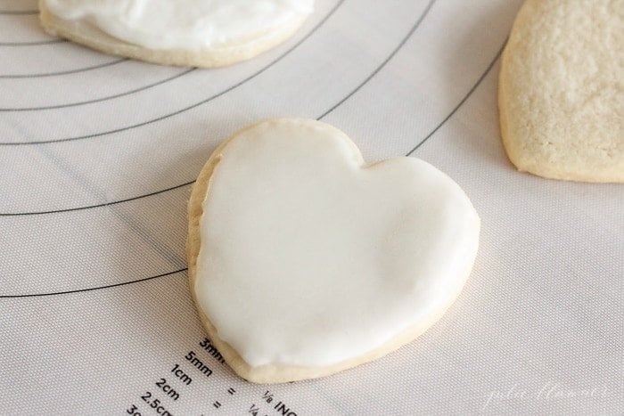 A heart shaped sugar cookie topped with white buttercream frosting for sugar cookies.