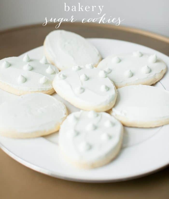 A white plate full of white frosted easy sugar cookies for Easter in the shape of eggs.