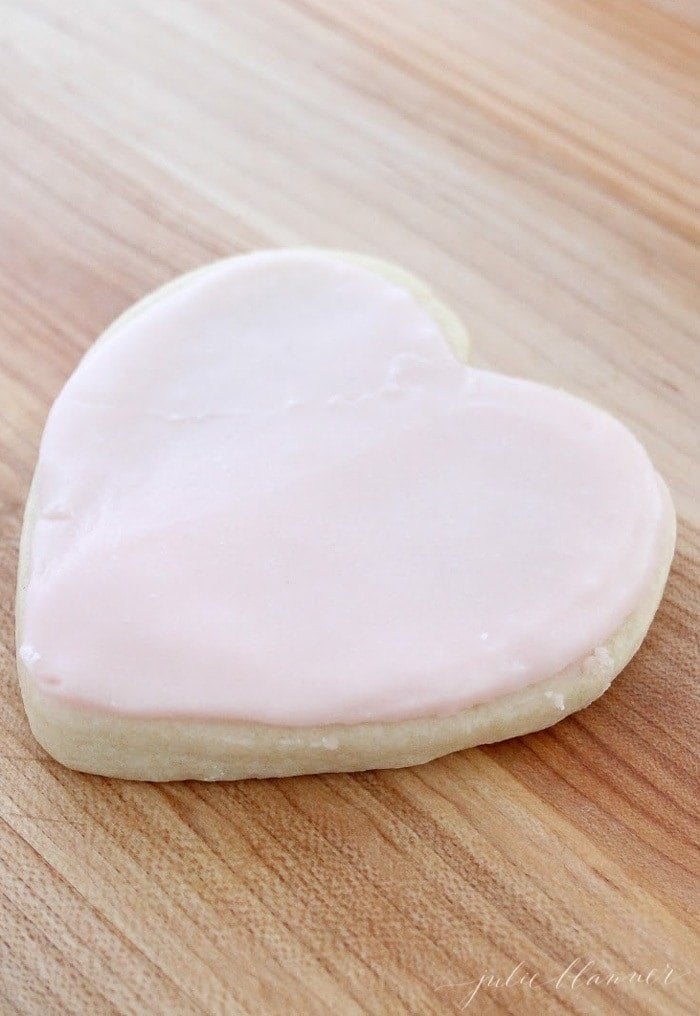An iced sugar cookie in the shape of a heart, topped with buttercream sugar cookie frosting recipe.