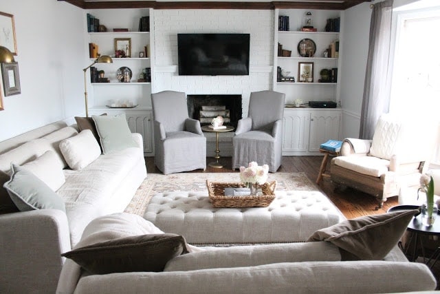 A living room filled with furniture and a fire place. Shelves surround the fire place and a flat screen TV hangs over it as well.
