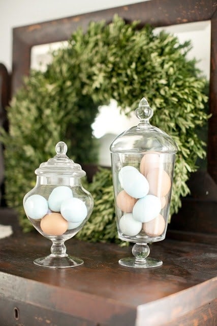 Two glass vases with multicolored eggs inside.
