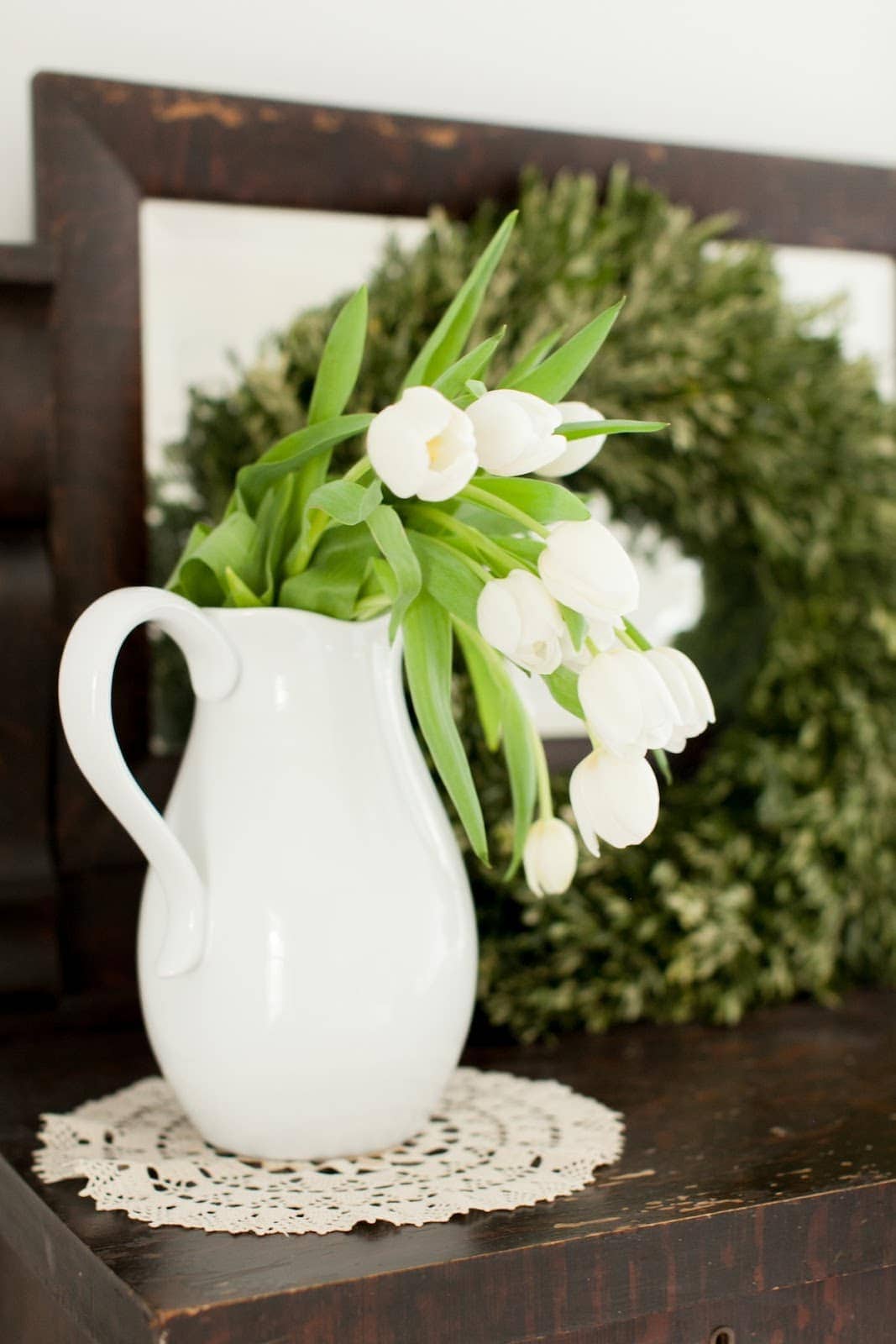 A white pitcher filled with white tulips.