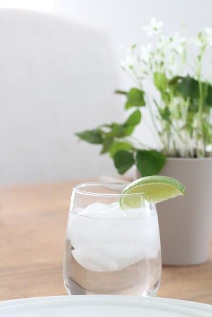 A drink and a vase of flowers on the table.